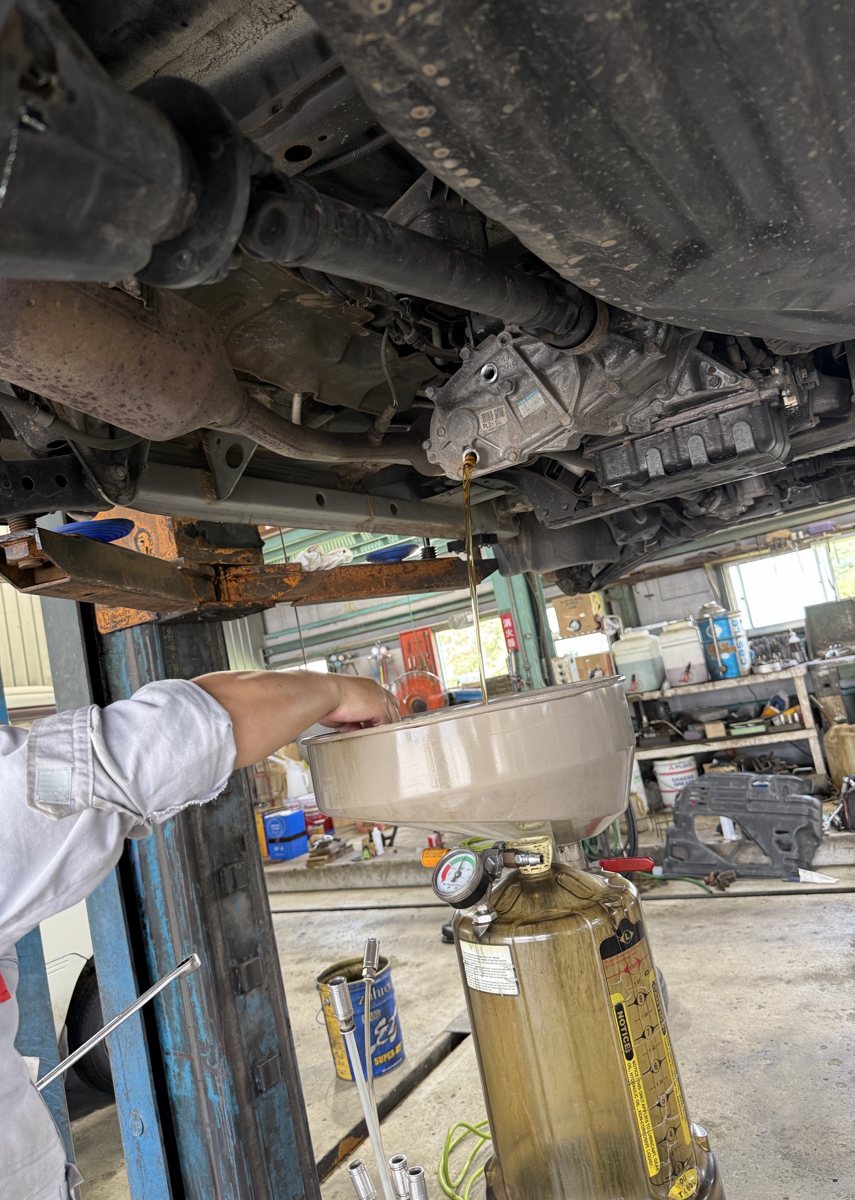 車の下からオイルを抜いている様子